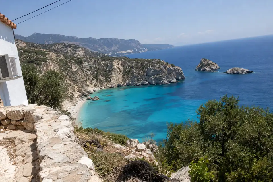 Een ondiepe turquoise lagune, kale eilandjes voor de kust, hoge kalkstenen kliffen boven zee.